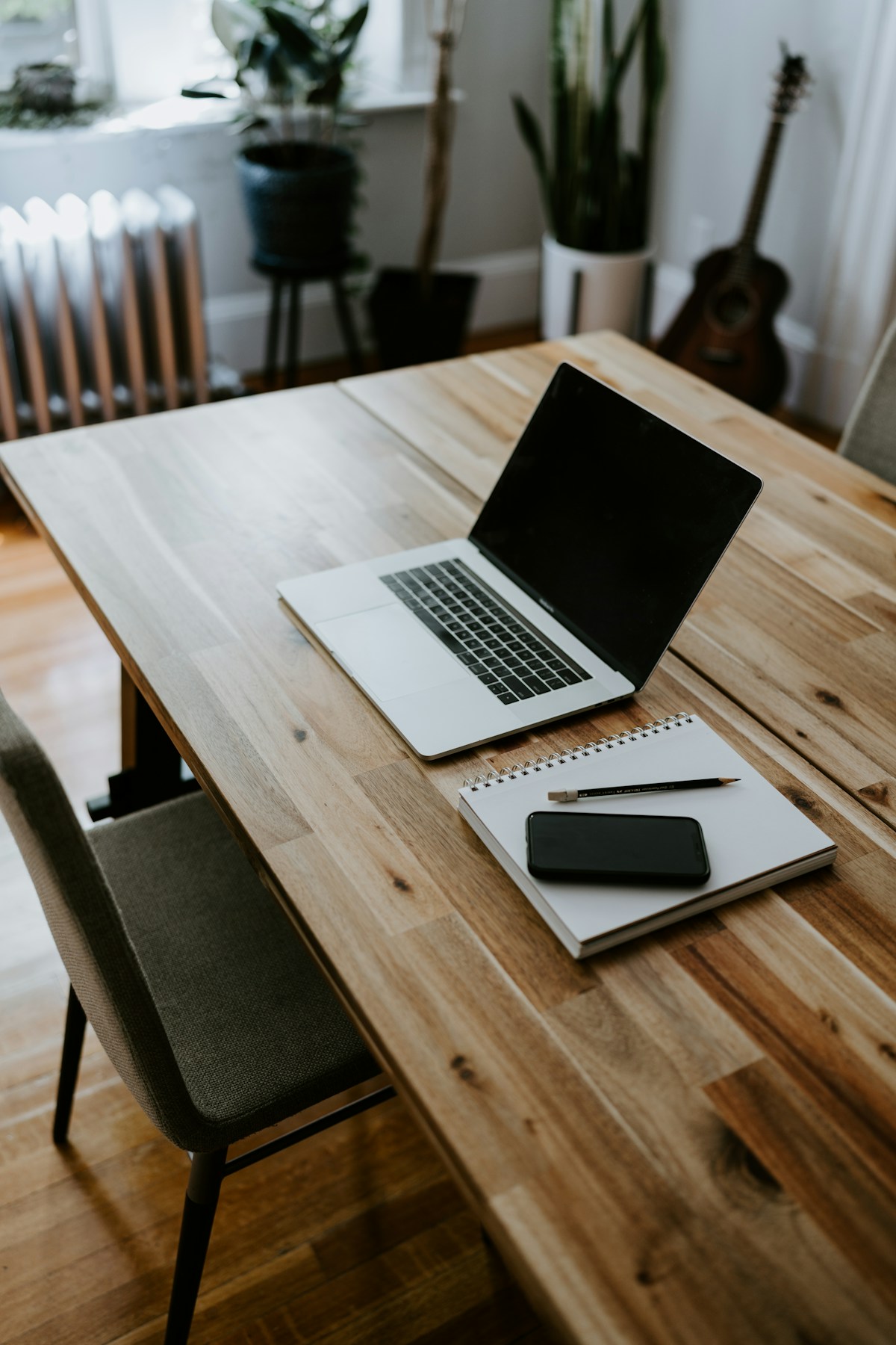 A laptop and notebook on a sunlit desk